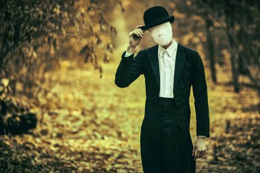 Cadılar Bayramı. Gizemli korku romanı. Yüzünde alçı bandajlı, melon şapkalı ve siyah ceketli tuhaf ve ürpertici bir beyefendi eski bir sonbahar parkında duruyor. Cadılar Bayramı. Boşluğu kopyala.