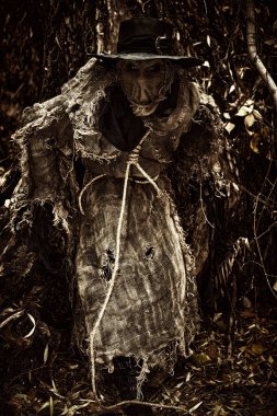 A terrible Scarecrow with a canvas bag on his head and in a sackcloth robe hid in a dense forest. Evil forest sorcerer. Halloween Tales. Horror, thriller. clipart