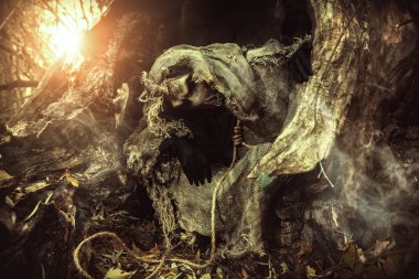 Korkunç bir korkuluk kafasında bez bir kaftanla sık bir ormanda saklanmış bir çuval bezle. Kötü orman büyücüsü. Cadılar Bayramı Masalları. Korku, gerilim.