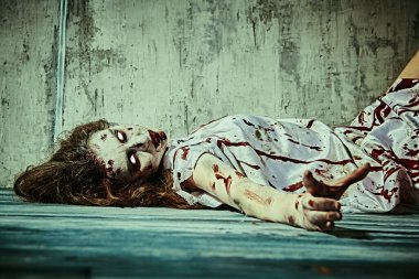 Şeytan tarafından ele geçirilmiş korkunç şekilsiz bir kadın şeytan çıkarma ayininden sonra kanla kaplı karanlık bir odada yatıyor. Ürkütücü zombi kadın. Korku, gerilim. Cadılar Bayramı.