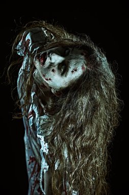 Korku filmi, gerilim. Karanlık bir odada soluk gözlü ve kanla kaplı ürkütücü takıntılı bir kadının korku sahnesi. Kana susamış zombi kadın. Cadılar Bayramı.