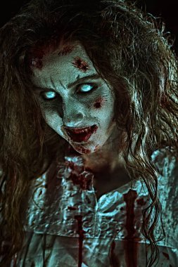 Şeytan tarafından ele geçirilmiş biçimsiz kanlı bir kadın solgun gözlerle kameraya bakar ve gülümser. Zombi kadın. Korku, gerilim. Cadılar Bayramı. 
