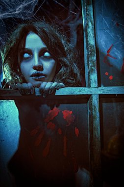 Horror scene. A scary ghost girl looks out of the window of an old abandoned house. Haunted house. Halloween. clipart