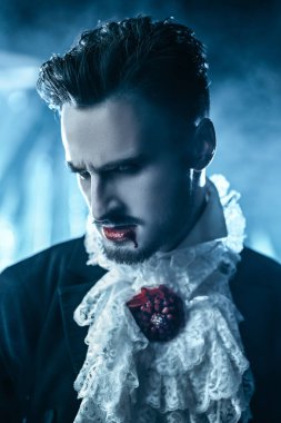 Vampirler. 19. yüzyıldan kalma zarif bir takım elbiseyle dudaklarında kanla kötü kalpli yakışıklı vampir adam eski kalesinde duruyor. Cadılar Bayramı.