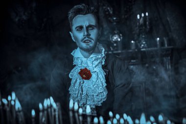 Kızgın bakışları olan kana susamış bir vampir yanan mumların arasında dişlerini göstererek karanlık ve kasvetli kalesini aydınlatıyor. Cadılar Bayramı.