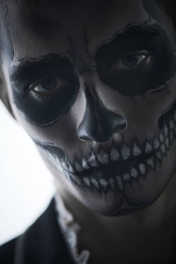 Cadılar Bayramı. Beyaz bir arka planda kafatası makyajı yapmış şeytani yakışıklı bir adamın yakın plan portresi. Dia de los muertos. Ölülerin Günü. 
