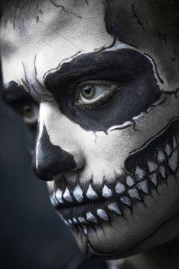 Ölüler Günü. Cadılar Bayramı. Karanlık bir arka planda kafatası makyajı yapmış şeytani yakışıklı bir adamın yakın plan portresi. Dia de los muertos. 