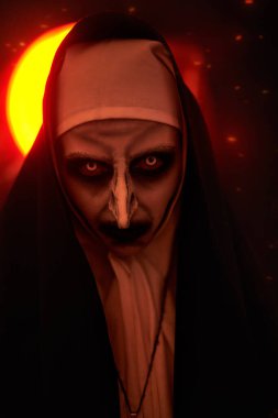 Portrait of a terrible cursed nun in the light of hellfire. Halloween and Horrors. clipart