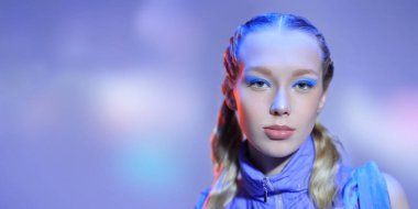 Güzellik, makyaj ve kozmetik. Güzel bir kızın portresi dalgalı sarı saçları ve mor arka planda poz veren turkuaz göz makyajı. Boşluğu kopyala.