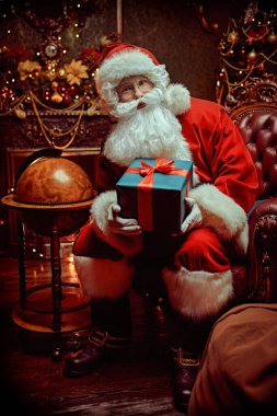 Nazik Noel Baba elinde bir Noel hediyesiyle güzel bir Noel ortamında bir koltukta oturur. Mutlu Noeller ve mutlu yıllar.!