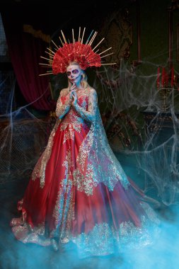 Santa Muerte 'de. Güzel Calavera Catrina, şenlikli, altın kırmızısı elbisesi ve çiçekli başlığıyla eski kalede duruyor. Ölüler Günü. Kafatası şekeri kız. Dia de los Muertos. Cadılar Bayramı.