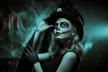 Calavera Catrina. Karnaval başlığıyla poz veren Kafatası Şekeri bir kızın sanat portresi ve gizemli kırmızı ve mavi ışıkta büyük bir çiçek. Ölüler Günü. Dia de los Muertos. Cadılar Bayramı.