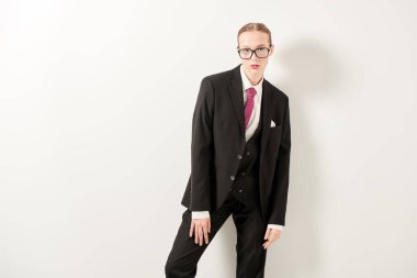 İş stili. Güzel bir kızın stüdyo portresi. Katı makyaj ve saç stili. Zarif siyah bir takım elbise ve beyaz arka planda şık gözlük takıyor. Moda fotoğrafı. Boşluğu kopyala.