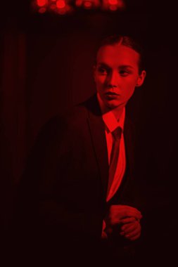 Şık bir takım elbise, beyaz gömlek ve içinde kırmızı ışık bulunan lüks bir iç mekanda poz veren kendine güvenen muhteşem bir kadının portresi. Lüks bir iş tarzı. Moda. İş kıyafetleri tarzı.