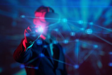 Sanal Gerçeklik gözlüklü bir erkek işadamı işinin 3 boyutlu bir hologramını yönetiyor. İş stratejileri ve taktikleri. Geleceğin bilgi teknolojileri.