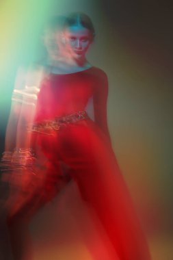 Göz kamaştırıcı bayan dansçı, parlak mücevherleri olan zarif kırmızı elbiseler içinde Latin dansı yapıyor. Moda ve güzellik. Bale gösterisi. Bulanık efektli stüdyo resmi.