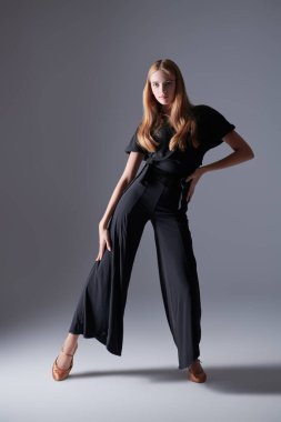 Stüdyoda siyah bluzla, pantolonla ve ayakkabılarla dans eden güzel bir kız. Güzellik ve Moda. Modern bale dansları.