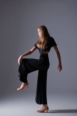 Modern bale dansları. Stüdyoda siyah bluz, pantolon ve ayakkabılarla dans eden güzel bir kızın tam boy portresi. Güzellik ve Moda.