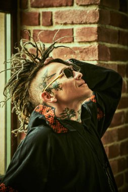 Kafasında ve boynunda etnik dövmeler ve punk stili Mohawk rastaları olan olgun, vahşi bir adamın portresi. Serseri ve rock kültürü. 