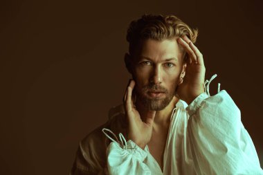 Beyaz, klasik gömlekli, kahverengi arka planda geniş kollu, olgun bir adamın stüdyo fotoğrafı. Tarihi portre, 19. yüzyıl sonu - 20. yüzyıl başı. Erkek güzeli. Boşluğu kopyala.