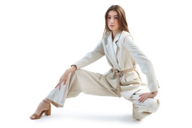 Beyaz arka planda bol bej bir takım elbiseyle poz veren güzel bir kadın modelin moda çekimi. Kadın modası. Zarif bir tarz. Tam boy stüdyo resmi.. 