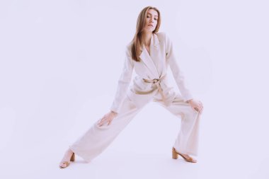 Beyaz bir stüdyo arka planında bol bej bir takım elbise giymiş güzel kahverengi saçlı bir mankenin tam boy çekimi. Zarif bir tarz. Moda fotoğrafı.. 