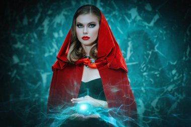 Peri masalları. Kırmızı pelerin ve siyah elbise giyen genç ve güzel bir büyücü sihirli bir kristal küre ile ortaya çıkıyor. Cadılar Bayramı büyüsü.