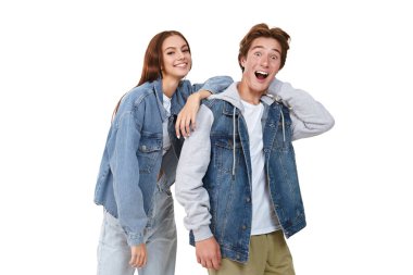 Moda giysileri içindeki iki duygusal genç beyaz arka planda yan yana durup gülümsüyor. Gençler için Denim modası. 