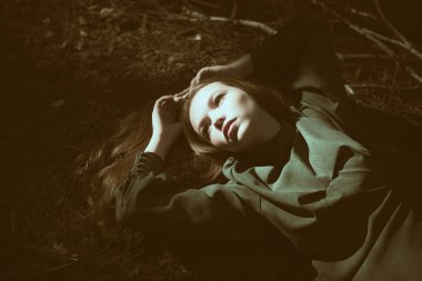 Fantezi, peri masalı kahramanı. Yeşil elbiseli büyüleyici bir kız, güneş ışınlarıyla aydınlatılan karanlık büyülü bir ormanda yerde yatıyor. Efsaneler ve peri masalları. 