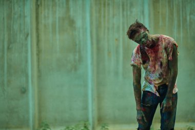 Zombi kıyameti. Sinirli kanlı zombi adam fotokopi alanı olan kasvetli kirli bir arka plana karşı. Cadılar Bayramı. Korku filmi. 