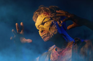 Karanlıktan gizlice gözetleyen çirkin kanlı bir zombi portresi. Esmer dumanlı arka plan. Cadılar Bayramı. Korku filmi. 