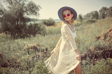 Güneşli bir yaz gününde açık havada poz veren boho tarzı kıyafetler ve mücevherlerle güzel sarışın bir kızın moda çekimi. Yaz bohem ve hippi tarzı. Moda ve güzellik. 