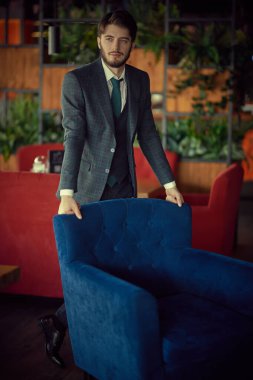 İş adamı. Lüks dairelerde duran zarif klasik takım elbiseli yakışıklı bir esmer adam portresi. Erkek güzelliği, moda. İş biçimi.