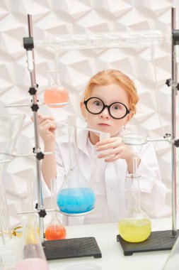 Meraklı küçük bir kız laboratuarda deneyler yapıyor. Bilim ve eğitim.