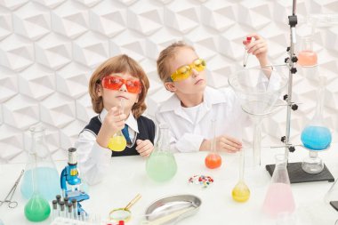 Çocukların erken gelişimi. Gözlüklü iki çocuk laboratuvarda kimyasal deneyler yapıyor. Eğitici kavram. 