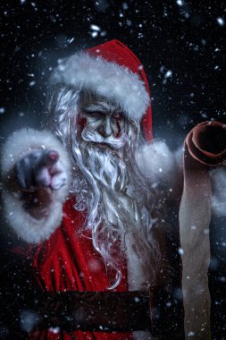 Korkunç bir Noel Baba zombisinin portresi. Geceleri kar altında dikilip işaret parmağını kameraya doğrultuyor. Noel 'de kabus. Cadılar Bayramı.