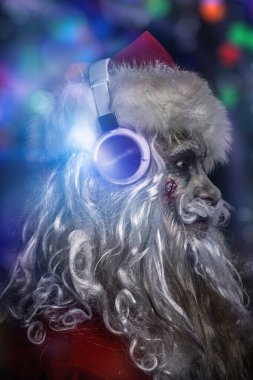 Zombiler için Noel partisi. Korkunç ve havalı DJ zombi Noel Baba 'nın kulaklıklı portresi. Renkli ışıkları olan siyah bir arkaplan. Cadılar Bayramı.