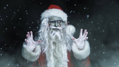Korkunç bir zombi Noel Baba portresi kanlı sakallı ve gözü yanan, kameraya bakıp şeytanca gülen. Siyah arka plan. Noel, Yeni Yıl ve Cadılar Bayramı.
