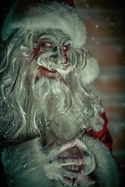 Kameraya bakıp şeytanca gülen, kanlı sakallı, neşeli ve korkunç Noel Baba 'nın portresi. Karlı ahşap bir arka plan. Noel, Yeni Yıl ve Cadılar Bayramı.