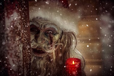 Korkunç bir Noel Baba zombisinin portresi. Geceleri kar altında elinde mumla sinsice gülüyor. Noel 'de kabus. Cadılar Bayramı.