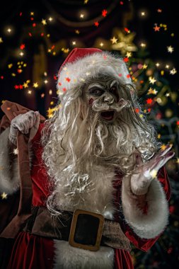 Kameraya bakıp şeytanca gülen, kanlı sakallı, neşeli ve korkunç Noel Baba 'nın portresi. Konfetili yılbaşı arkaplanı. Noel, Yeni Yıl ve Cadılar Bayramı.