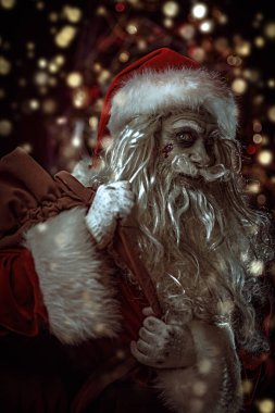Noel ve Cadılar Bayramı. Korkunç Zombi Noel Baba arkasında hediyelerle dolu bir çantayla Noel süslemesiyle örümcek ağlarına dolanmış ve şeytanca gülümsüyor..