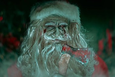 Şeytani zombi Noel Baba elinde baltayla gece odasında örümcek ağlarına sarılmış ve sinsice gülümseyen bir baltayla duruyor. Noel 'de kabus. Cadılar Bayramı.