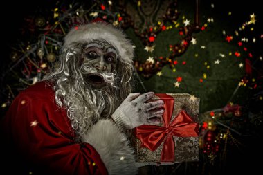 Noel ve Cadılar Bayramı. Korkunç Zombi Noel Baba elinde hediye kutusuyla Noel süsüsüyle örümcek ağlarına dolanmış ve şeytanca gülümsüyor..