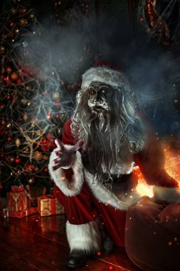 Noel ve Cadılar Bayramı. Korkunç Zombi Noel Baba bir Noel ağacının yanında oturuyor, örümcek ağlarına dolanmış ve şeytanca gülüyor..