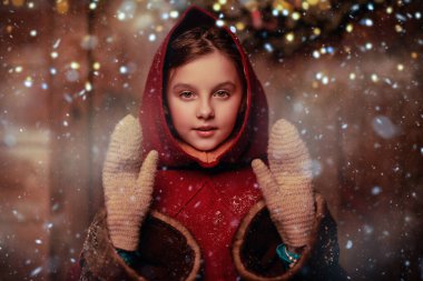 Noel mucizeleri ve hayalleri. Ortaçağ kıyafetleri içindeki melek gibi bir kız, karlı bir Noel arifesinde bir evin yanında duruyor. Şiddetli kar yağışı ve parlayan ışıklarla sihirli Noel gecesi.