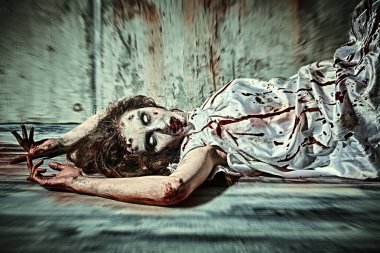 Ürkütücü zombi kadın. Şeytan tarafından ele geçirilmiş korkunç şekilsiz bir kadın şeytan çıkarma ayininden sonra kanla kaplı karanlık bir odada yatıyor. Korku, gerilim. Cadılar Bayramı.