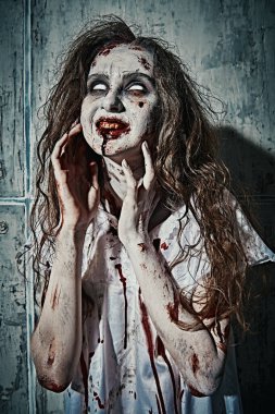 Şeytan tarafından ele geçirilmiş biçimsiz kanlı bir kadın solgun gözlerle yukarı bakıyor ve gülüyor. Zombi kadın. Korku, gerilim. Cadılar Bayramı. 