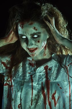 Solgun gözlü kana susamış bir zombi kadın kameraya gülümsüyor ve kanlı dişlerini gösteriyor. Şeytan ele geçirilmiş kadın. Korku, gerilim. Cadılar Bayramı. 