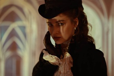 Zarif bir elbise içindeki güzel bir bayanın klasik portresi ve eski bir binanın penceresinin gölgesinde duran bir şapka. 19. yüzyılın sonları - 20. yüzyıl başları.